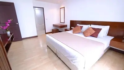a bedroom with a large white bed with brown pillows at Ploenchit Mansion in Bangkok