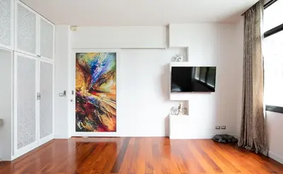 a living room with a painting on the wall and a tv at Benviar Tonson Residence in Bangkok