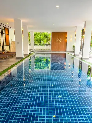 a swimming pool with a blue tile floor in a building at Benviar Tonson Residence in Bangkok