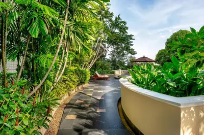 a resort walkway with palm trees and a bench at Conrad Bangkok Residences in Bangkok