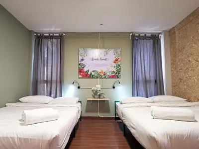 a room with three beds and a painting on the wall at FORESTTEL.BKK in Bangkok