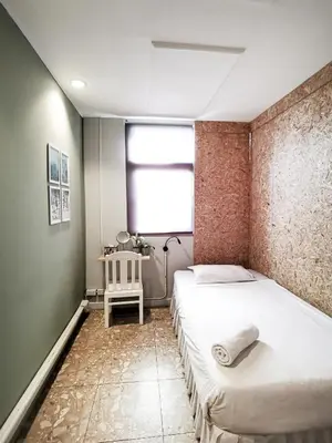 a bedroom with two beds and a window and a table at FORESTTEL.BKK in Bangkok