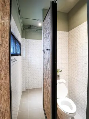 a bathroom with a toilet and a shower with a door at FORESTTEL.BKK in Bangkok
