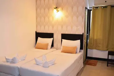two beds in a room with white sheets and pillows at Erawan House in Bangkok