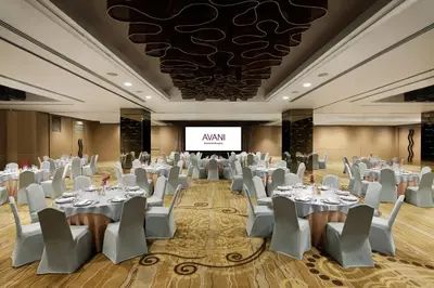 a banquet hall with white tables and chairs and a screen at Avani Ratchada Bangkok in Bangkok