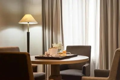 a room with a table with chairs and a lamp at Avani Ratchada Bangkok in Bangkok