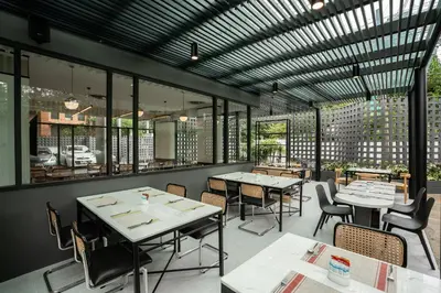 a restaurant with tables and chairs and windows at Hotel Amber Sukhumvit 85 in Bangkok