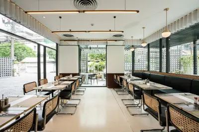 a dining room with tables and chairs and windows at Hotel Amber Sukhumvit 85 in Bangkok