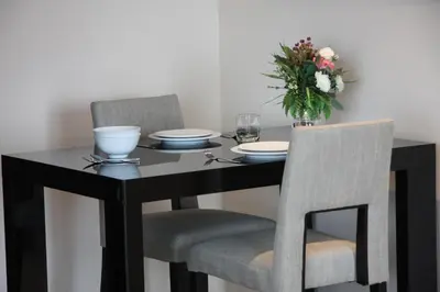 a black table with two chairs and a vase of flowers at Park Village Rama II in Bangkok