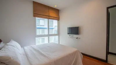 a bedroom with a white bed and a window at Prime 11, High Floor Over Pool, 2 Br, 2 Balcony in Bangkok