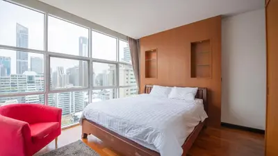 a bedroom with a bed and a red chair at Prime 11, High Floor Over Pool, 2 Br, 2 Balcony in Bangkok