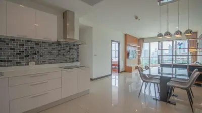 a kitchen with white cabinets and a table and chairs at Prime 11, High Floor Over Pool, 2 Br, 2 Balcony in Bangkok