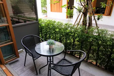 a glass table and two chairs on a patio at Vali Villa Bangkok in Bangkok