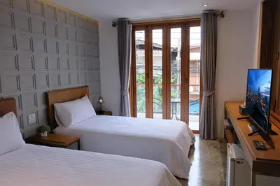 a hotel room with two beds and a flat screen tv at Vali Villa Bangkok in Bangkok