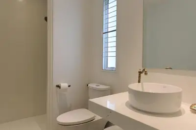 a white bathroom with a sink and a toilet at Vali Villa Bangkok in Bangkok
