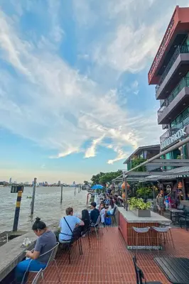 a group of people sitting at a table by the water at Baan Wanglang Riverside, Bangkok in Bangkok
