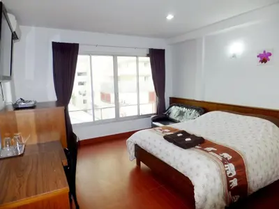 a bedroom with a bed and a table and a window at Orchid Inn in Bangkok