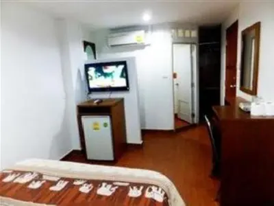 a living room with a tv and a bed in a room at Orchid Inn in Bangkok