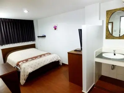 a bathroom with a bed and a sink and a mirror at Orchid Inn in Bangkok