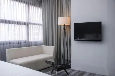a room with a couch and a tv and a chair at Holiday Inn Bangkok Sukhumvit by IHG in Bangkok