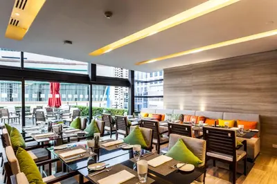 a restaurant with tables and chairs and a large window at Holiday Inn Bangkok Sukhumvit by IHG in Bangkok