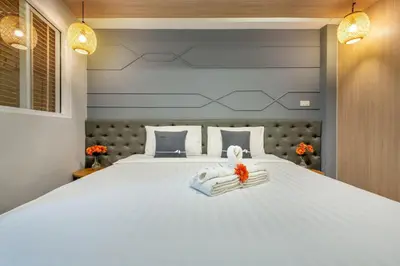 a bedroom with a large white bed with towels on it at Tori Prestige Bangkok Hotel in Bangkok
