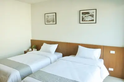 two beds in a room with white sheets at 24Residence Siriraj in Bangkok
