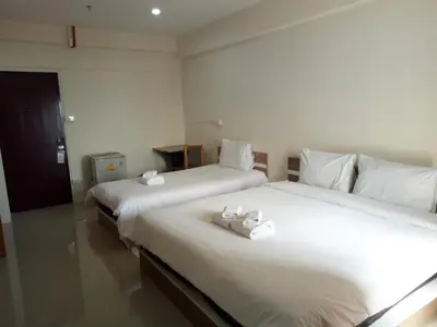 two beds in a hotel room with towels on them at Komol Residence Bangkok in Bangkok