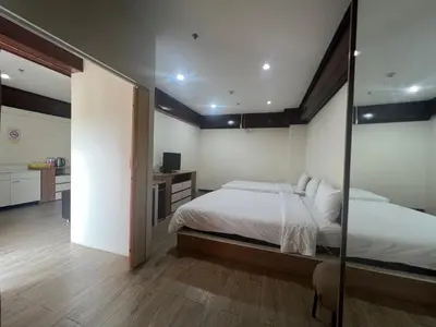 a bedroom with a large bed and a mirror at Komol Residence Bangkok in Bangkok