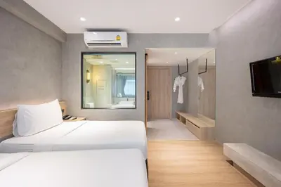a hotel room with two beds and a television at Loft Bangkok Hotel in Bangkok