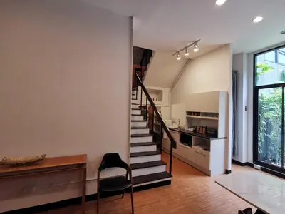 a living room with a staircase and a kitchen at A Bangkok Journey in Bangkok