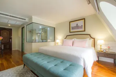 a bedroom with a large white bed and a blue bench at Daraya Boutique Hotel in Bangkok