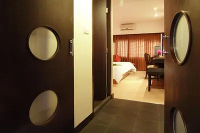 a room with two mirrors on the wall and a bedroom at Rose Hotel in Bangkok