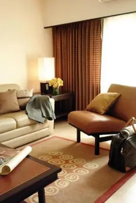 a living room with a couch and a chair at Rose Hotel in Bangkok