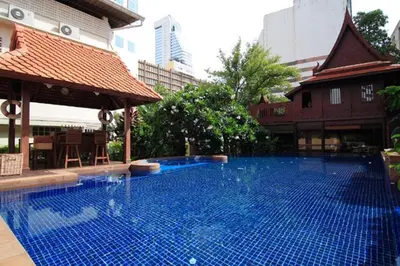 a large blue swimming pool in a building at Rose Hotel in Bangkok