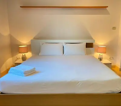 a bedroom with a white bed with two lamps at PACIFIC RESIDENCE 39 in Bangkok