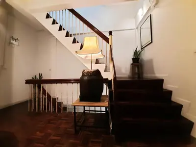 a stairway with a lamp on a table and a stair case at Pingplalee Female House in Bangkok