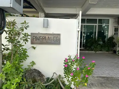 a sign on the side of a building with flowers at Pingplalee Female House in Bangkok