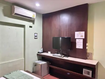 a hotel room with a tv and a desk with a computer at Sabye Bangkok in Bangkok