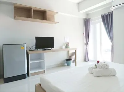 a white room with a bed and a desk with a television at JVAPLACE in Nonthaburi