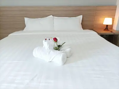 a white bed with a rose and towels on it at JVAPLACE in Nonthaburi
