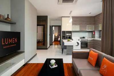 a living room with a couch and a kitchen at Lumen Bangkok Srinakarin in Bangkok