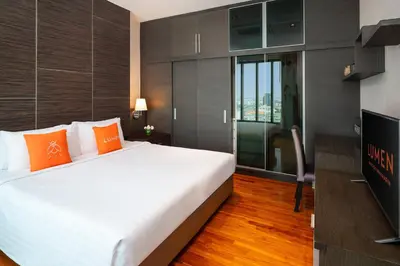 a bedroom with a large white bed with orange pillows at Lumen Bangkok Srinakarin in Bangkok