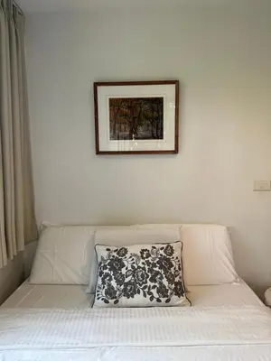 a picture above a couch with a pillow on it at Cozycomo Bangkok in Bangkok