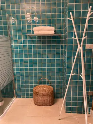 a green tiled bathroom with a basket and towels at Cozycomo Bangkok in Bangkok