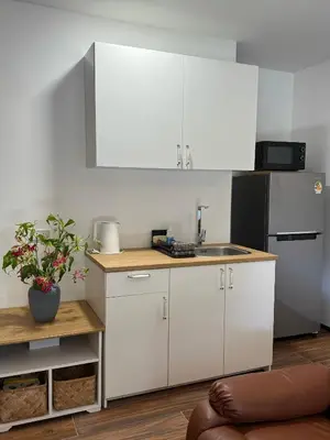 a kitchen with white cabinets and a sink and a refrigerator at Cozycomo Bangkok in Bangkok