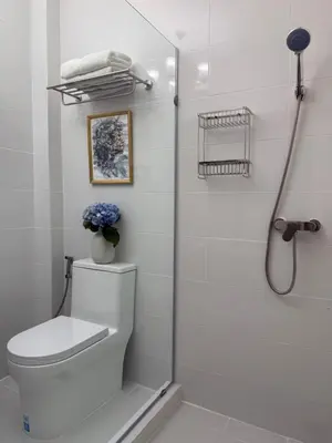 a white bathroom with a toilet and a shower at Cozycomo Bangkok in Bangkok