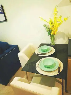 a black table with two plates and a vase with flowers at Moonlight Goddess in Bangkok