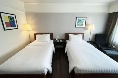 two beds in a hotel room with white sheets at Le Siam Hotel Silom Bangkok by PCL in Bangkok