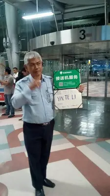 an older man is holding a sign in a building at IMPACT Don Mueang Bangkok Guest House in Nonthaburi